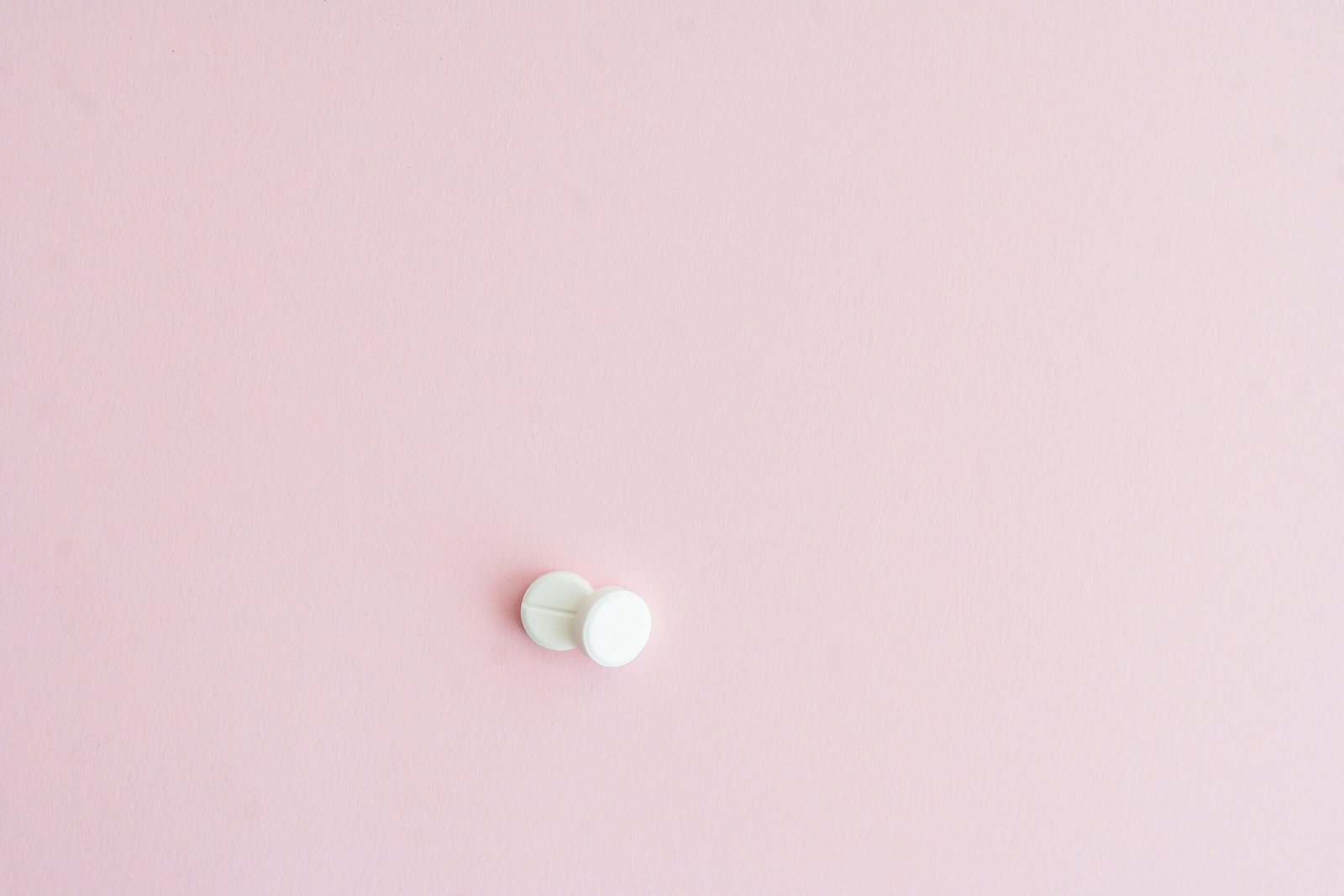 Two white tablets on a soft pink background, showcasing minimalist design.